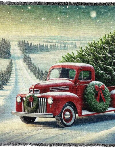 Woven throw blanket depicting a vintage red pickup truck carrying a Christmas tree through a snowy landscape.