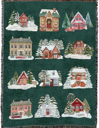 A green woven throw blanket featuring a grid of twelve different winter houses surrounded by snow and pine trees.