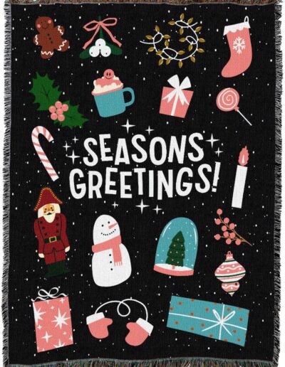 A black throw blanket featuring the text SEASONS GREETINGS! surrounded by icons of a gingerbread man, stocking, candy cane, nutcracker, snowman, gifts, and holiday ornaments.