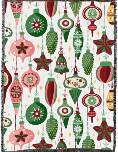 Woven blanket featuring a repeating pattern of various Christmas ornaments in shades of red, green, and pink on a white background.