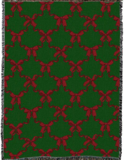 Green woven throw blanket featuring a repeating red bow pattern and fringed edges.